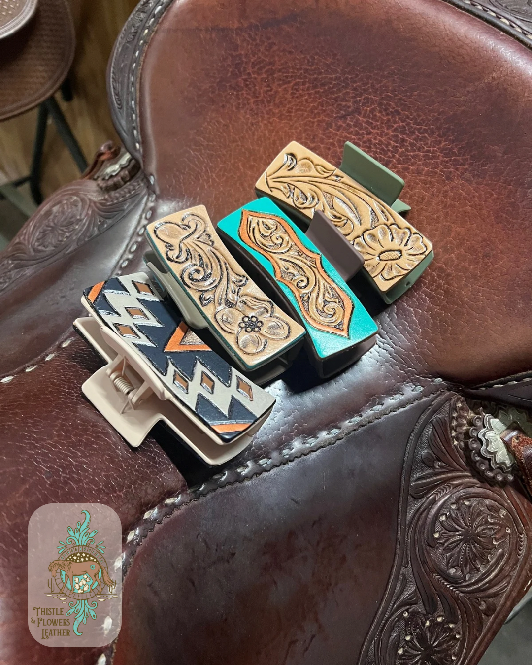 4 large hair clips from the homestead collection on a saddle seat. Photo is taken at a slight angle. Logo is in the bottom left of photo.