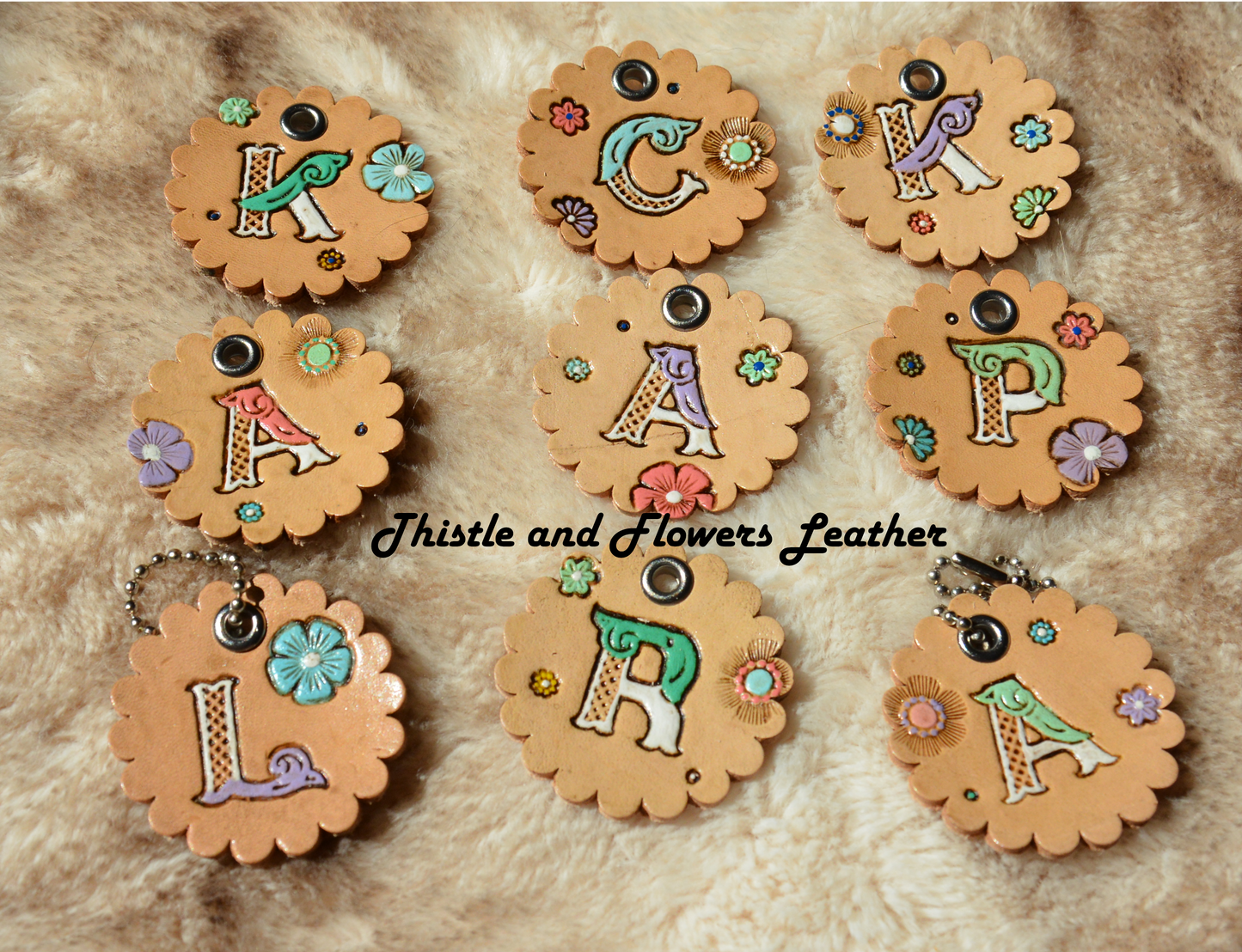 Tooled leather keychain with beaded connector. Scalloped edges, letters, "K" "L" "P" "A" "C" "R" "K" "A" "A" with white and other colors. Multicolored flowers.. Antiqued. Each letter is on a seperate keychain with different flowers.