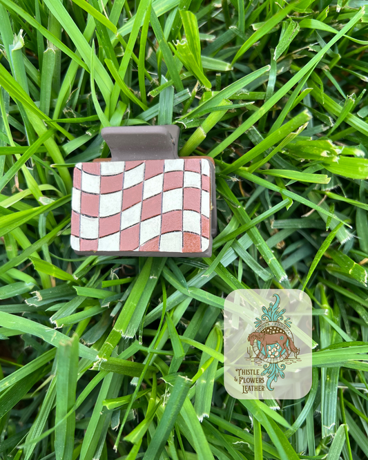 Brown medium sized base clip with checkerboard tooled and painted pattern in brown and white. Photographed on grass with logo on bottom right.