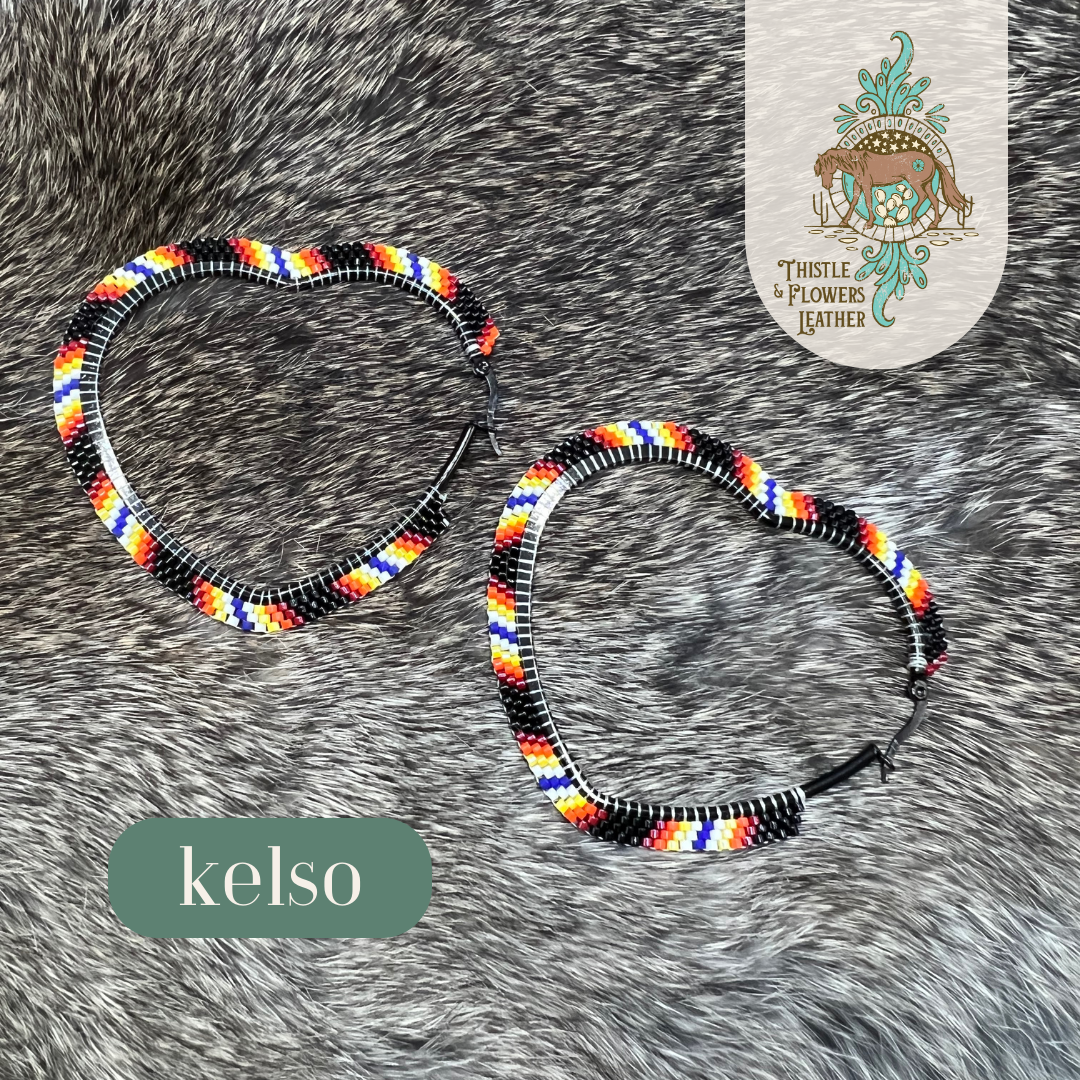 heart shaped hoops with western stripes pattern. black, red, orange, yellow, white and blue beads. Earrings are laying on rabbit fur, and "Kelso" is on the image to describe the style.