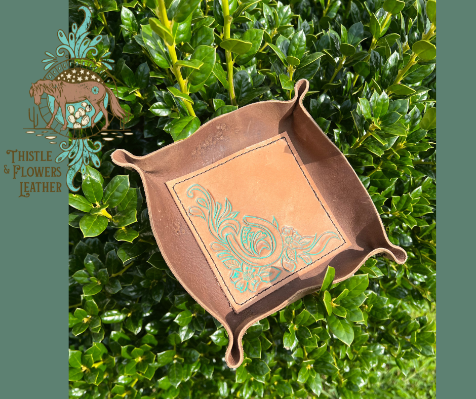 Leather valet tray with chocolate colored brown leather around exterior, and tooled veg tanned center. Tooling is of a horseshoe and floral scrolls.