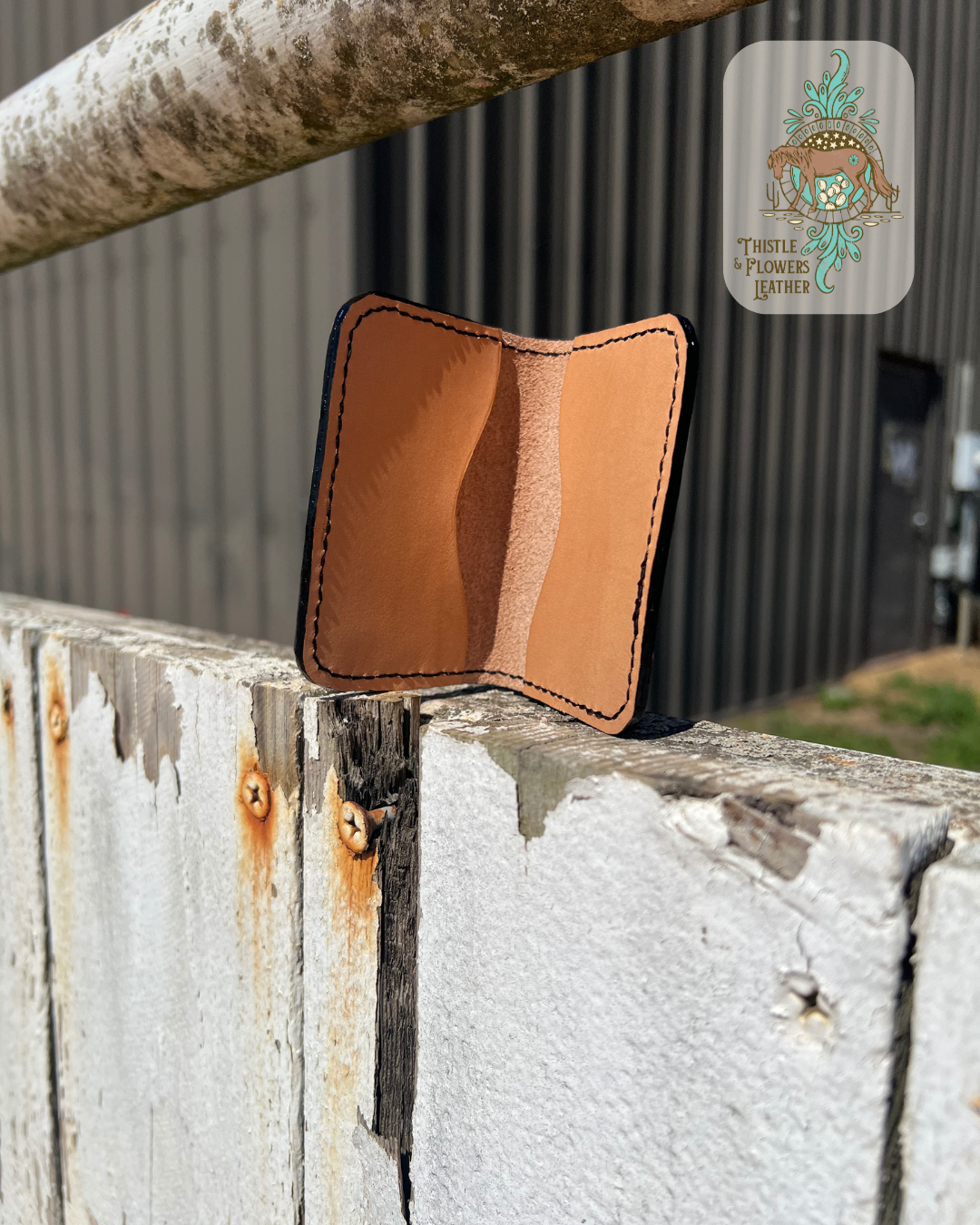 Interior of card holder showing pockets and stitching. Cardholder is on arena fence. Logo is in top right corner of photo.