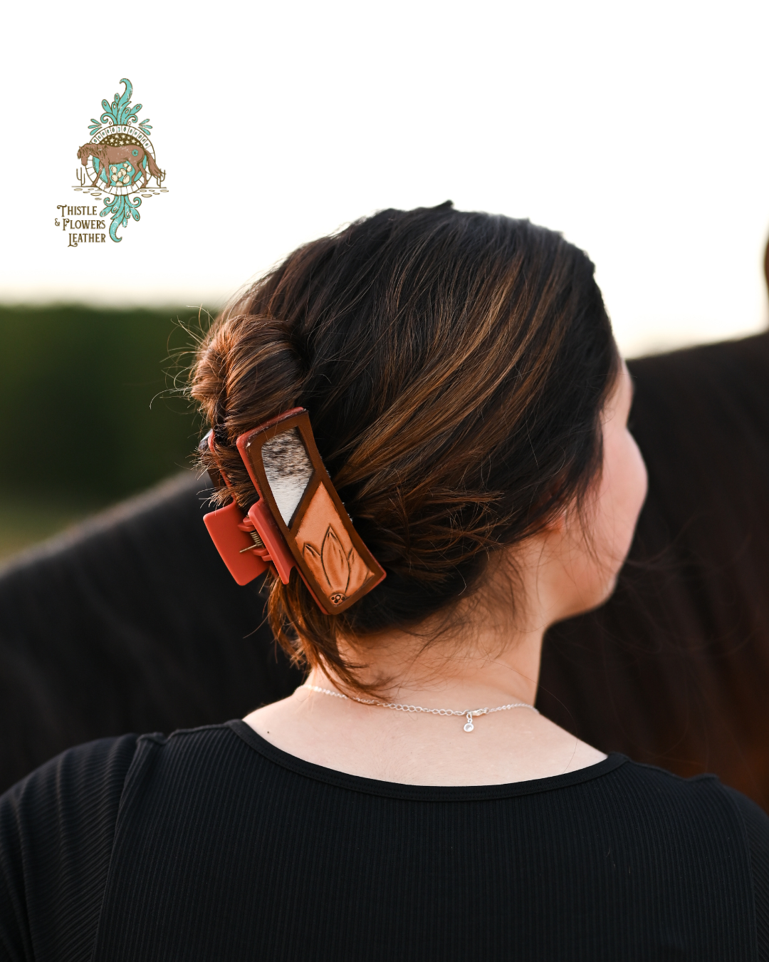 Brunette woman with horse, woman has a tooled leather claw clip in her hair. Hair clip has a tooled flower, and a cowhide inlay. 