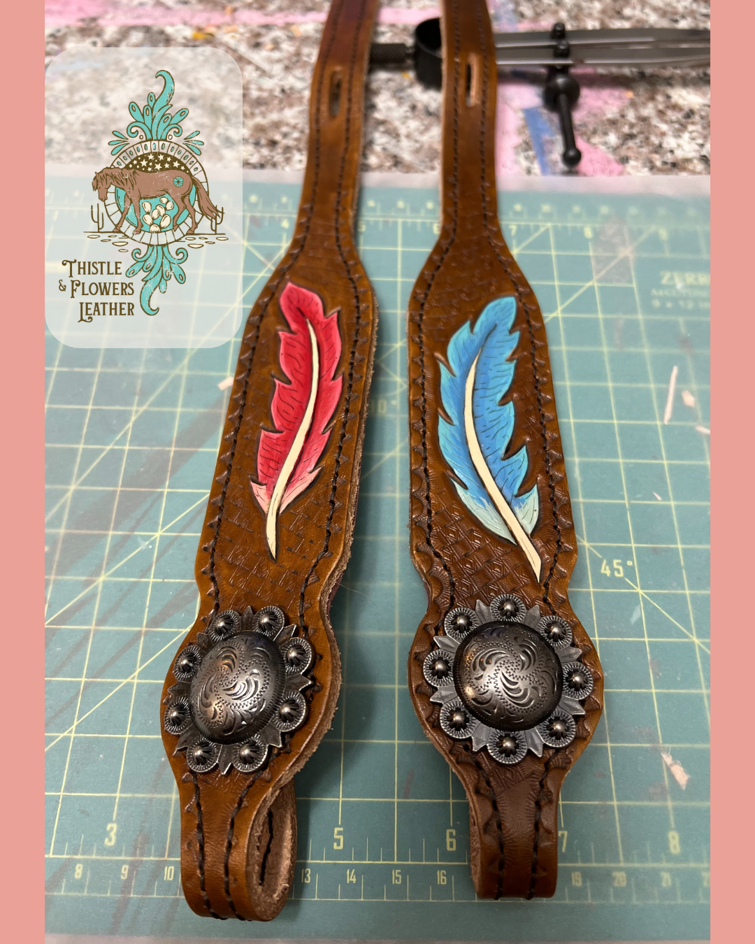 2 cheek pieces with tooled and painted feathers, one red, one blue, with silver berry concos and dyed leather. 