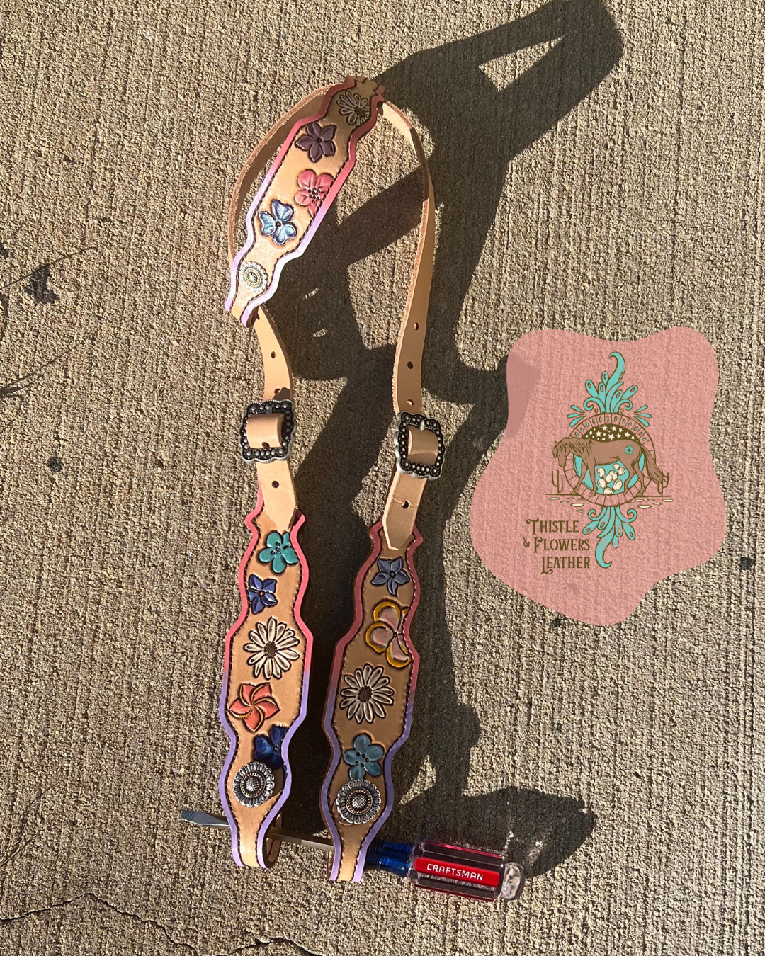 Example of a custom headstall. Florals and a purple-pink ombre border with silver buckles and silver with slight gold conchos. 