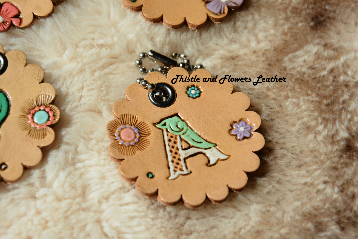 Tooled leather keychain with beaded connector. Scalloped edges, letter "A" with white and mint. Multicolored flowers. Antiqued.